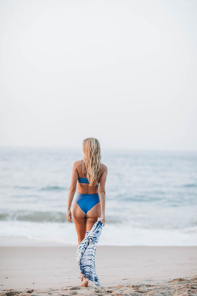 Woman at the ocean wearing the Maui high waisted bikini bottom in ocean stripe  by Summer Label Swimwear.  The best summer bikinis in Montauk NY